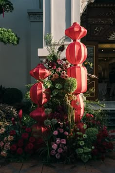 an arrangement of flowers and paper lanterns in front of a building