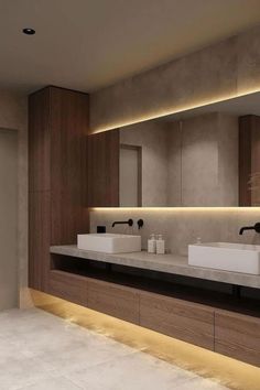 a modern bathroom with two sinks and large mirrors on the wall, along with lights above them