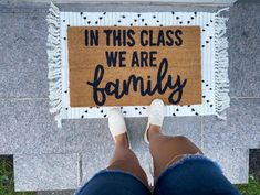 a person standing in front of a door mat that says in this class we are family