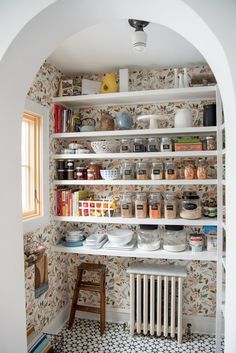 an arched doorway leads to a pantry with many items on shelves