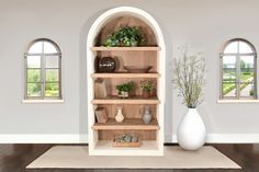 a white vase sitting on top of a wooden shelf next to a book case filled with plants