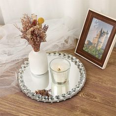 there is a vase with flowers and a candle on the table next to a picture