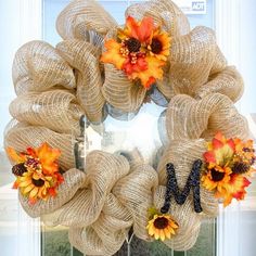 a wreath with sunflowers and fall leaves on the front door, hanging from a glass door