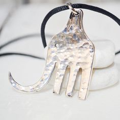 a silver hand shaped pendant on a black cord