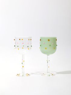 two glass goblets sitting next to each other on a white surface with confetti sprinkles all over them