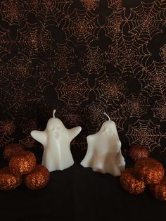 two white candles sitting next to each other on top of a black table covered in gold glitter balls