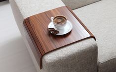 a cup of coffee sitting on top of a wooden tray next to a couch cushion