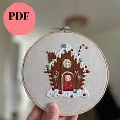 a hand holding up a small embroideryed house