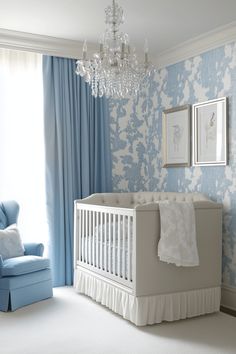 a baby's room with a crib, chair and chandelier in it