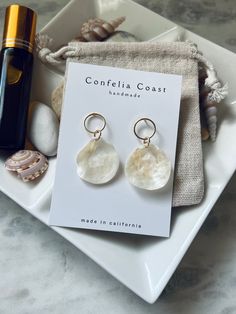 100% Handmade white jingle shells are arranged as beautiful drop earrings. They are very lightweight , great for all day wear. These nickel-free earrings feature gold-plated circle with stud back findings for comfort and simple aesthetic .  The shells for each pair are hand picked, and are meticulously assembled. These earrings have an organic and minimal look while still being very versatile. Would even make a beautiful addition to a beach bridal look. Please note,  each shell and by extension each pair have its own characteristics making them beautifully one of a kind . Jingle Shells, Beach Bridal, Simple Aesthetic, Nickel Free Earrings, Stud Jewelry, Circle Studs, Bridal Looks, Jewelry Earrings Dangle, Dangle Drop Earrings