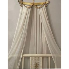 a canopy bed with white curtains and gold trimmings on the top, above it is