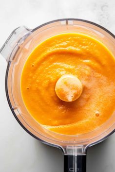 a blender filled with orange liquid on top of a white counter