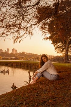 a woman sitting on the ground next to a body of water