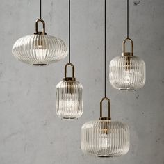 three clear glass pendants hanging from a ceiling fixture in a room with concrete walls