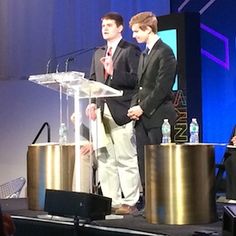 two men in suits are standing at a podium