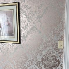 an ornate wallpapered room with a framed photograph on the wall next to it