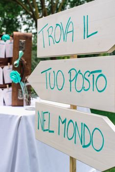 wooden signs pointing in different directions at an outdoor wedding reception with confetti on the table