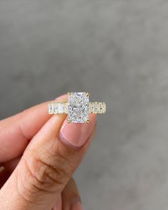 a woman's hand holding an engagement ring with two diamonds on it and the other side