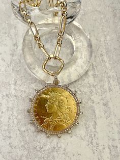 Beautiful reproduction vintage coin pendant, French Madagascar coin in a bezel with cubic zirconia stones. The bale attached to the coin is also encrusted with CZ stones. The coin is 22k gold plated and elegantly hangs from a multi link gold plated brass chain and a rope design spring lock clasp. The spring lock closure not only makes it easy to open and close the necklace for those with difficulty but adds to the creativity of the jewelry piece. Please see photograph of how to open the clasp. W Diamond Coin Pendant Medallion Jewelry, Luxury Gold Coin Medallion Necklace, Luxury Yellow Gold Coin Medallion Necklace, Gold Medallion Jewelry With Bezel Setting, Antique Gold Necklace With Diamond Accents, Luxury Gold Plated Coin Necklace, Luxury Yellow Gold Coin Pendant Necklace, Gold Round Coin Necklace For Anniversary, Yellow Gold Coin Necklace For Anniversary