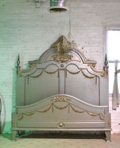 an old bed with gold trim and headboard in a room that has white brick walls