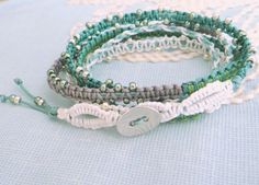 three different bracelets with beads and silver clasps on a blue cloth covered surface