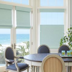 a dining room table with four chairs and a potted plant in the corner next to it