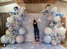 a woman standing on a ladder in front of balloons