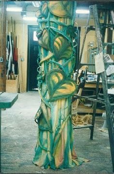 a tall green and yellow sculpture in a room filled with other things on the floor