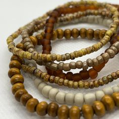 This is a lovely coordinated stack of 6 stretch seed bead and wood bracelets in earthy brown tones. Perfect for dressing up, a casual day out, or no occasion at all! Rearrange the bracelets to get the exact style you like, or add them to some of your existing favorites to customize your accessorizing. Looks fantastic paired with gold. Set includes one each of: deep bronze-brown, Picasso matte canary yellow, Picasso matte brown, off-white/stone solid color, metallic khaki, and one wood bead bracelet.  As a handmade item, each set will vary slightly due to randomization of patterns.  Giving as a gift? The 7" size is considered "standard" and fits a lot of teens and adults. Treating yourself? Measure your wrist to choose your desired size. Selecting a set that's a little larger means the stac Earthy Beaded Bracelets With Round Beads, Earthy Beaded Bracelets For Everyday, Casual Brown Beaded Necklace For The Beach, Casual Brown Beaded Necklace For Beach, Bohemian Brown Stretch Bracelet With Spacer Beads, Bohemian Brown Stretch Bracelet With Colorful Beads, Earthy Brown Beaded Bracelets With Round Beads, Casual Brown Beaded Necklaces With Colorful Beads, Brown Beaded Stretch Bracelet With Round Beads