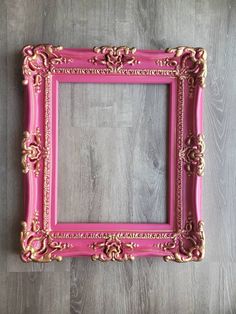 a pink and gold frame sitting on top of a wooden floor