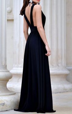 a woman standing in front of columns wearing a black dress with open back and high neck