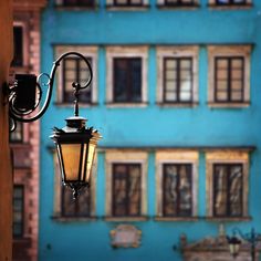 an old fashioned street light hanging from the side of a blue building with lots of windows