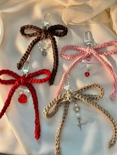 four different colored bows are tied together on a white cloth with red and clear beads