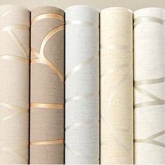 six rolls of wallpaper with different patterns and colors on each side, all lined up against one another