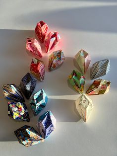 several origami pieces are arranged in a circle on a white surface with light coming through them