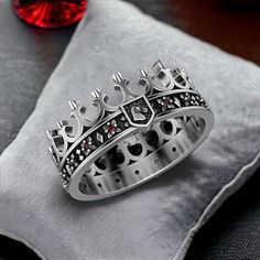 a crown ring sitting on top of a pillow next to a red crystal ball in the background