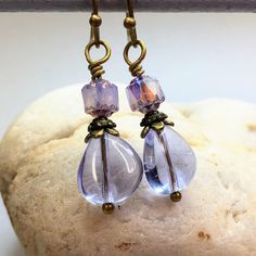 Enchanting lavender Czech glass teardrop earrings for an understated elegant look. Small iridescent beads top off lavender teardrops, adding just the right amount of sparkle. These cottagecore earrings make a stunning addition to any jewelry collection. Lavender is a versatile color, trending now. Beautiful with purple, green, pink, yellow, and more colors. Free gift packaging included. Earrings are carded and in an organza bag. Hypoallergenic ear wires (nickel and lead free). Select ear wire st Czech Glass Teardrop Earrings With Ear Wire, Elegant Lavender Beaded Earrings, Elegant Lavender Beaded Drop Earrings, Elegant Lavender Beaded Earrings With Dangling Beads, Purple Teardrop Wire-wrapped Earrings, Purple Teardrop Wire Wrapped Earrings, Lavender Teardrop Jewelry With Ear Wire, Elegant Hypoallergenic Teardrop Beaded Earrings, Purple Teardrop Pearl Drop Earrings