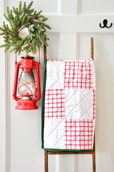 a red lantern hanging on the side of a white door next to a christmas tree