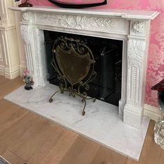 a white fireplace with a pink wall behind it and a hat on top of the fire place