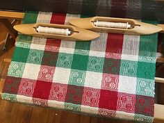 two wooden looms sitting on top of a green and red checkered table cloth