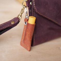 a leather purse with a keychain hanging from it's side and a lighter in the pocket