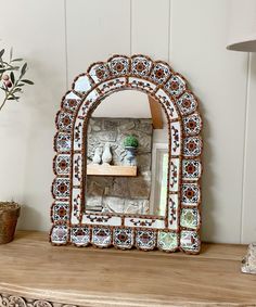 an ornate mirror sitting on top of a wooden shelf next to a potted plant