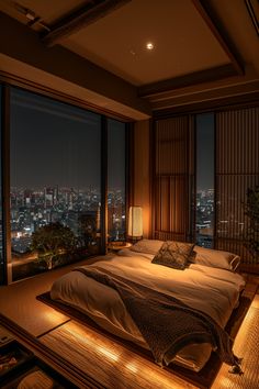 a large bed sitting in the middle of a bedroom next to a window with city lights on it