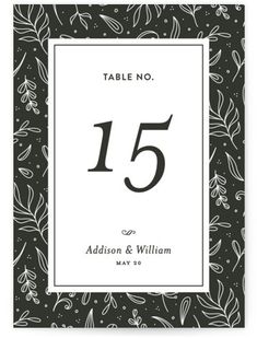 a black and white wedding table number card with leaves on the front, in an ornate frame