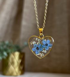 a heart shaped necklace with blue flowers in it