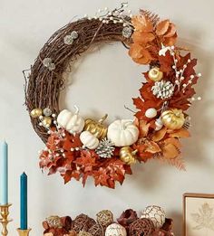 a wreath on the wall above a mantle with candles and other autumn decorations around it