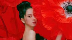 a woman with black hair standing in front of a red background and large flower petals