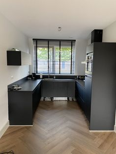 an empty kitchen with black cabinets and wood flooring