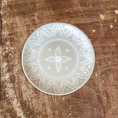 a white plate sitting on top of a wooden table next to a piece of wood