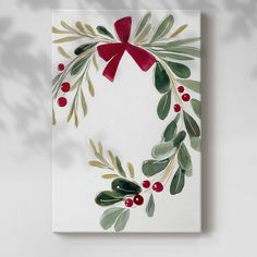 a christmas card with holly and red ribbon on it, hanging from a wall or ceiling